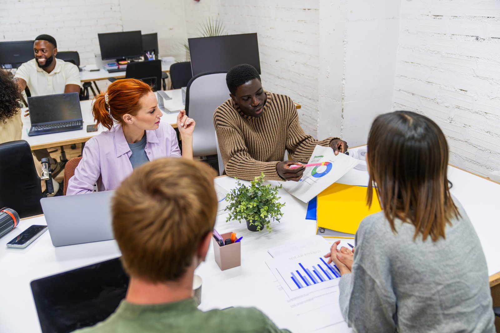 Marketing professionals discussing growth strategies in coworking space Diverse team of marketing professionals analyzing data and discussing growth strategies during a productive meeting in a modern coworking space