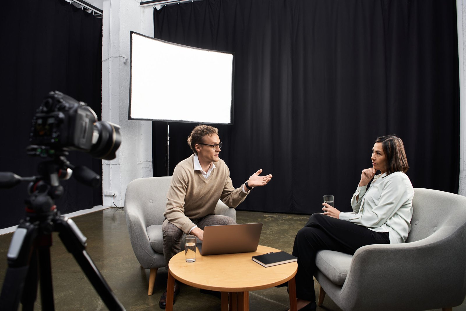 A knowledgeable journalist conducts a professional interview with a specialist in a modern studio environment. A knowledgeable journalist conducts a professional interview with a specialist in a modern studio environment.